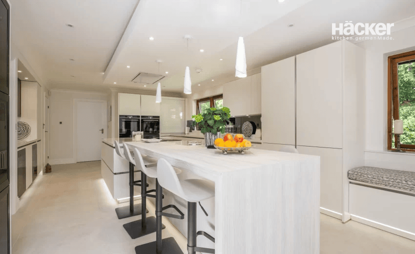 Serene white and oak kitchen design in West Chiltington with skylight and warm wood flooring