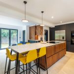 Walnut and matte black modern kitchen with island and yellow stools