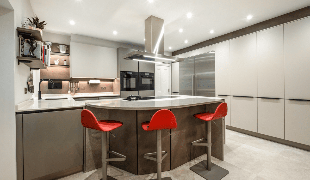 Modern kitchen with curved breakfast bar, handleless cabinets, large fridge and bright red stools