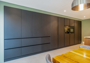 Modern open-plan kitchen dark wall units with ovens and concealed bar area