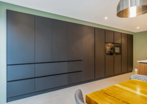 Modern open-plan kitchen dark wall units with ovens and concealed bar area