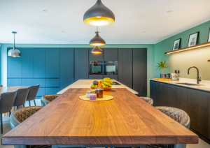 Modern open-plan kitchen with dark cabinets and wood effect island with breakfast bar