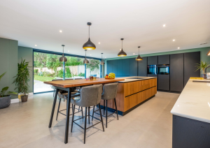 Modern open-plan kitchen with dark cabinets and wood effect island with breakfast bar