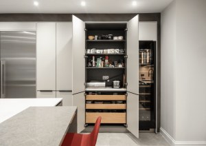Open larder cupboard in neutral tones with tall wine fridge.