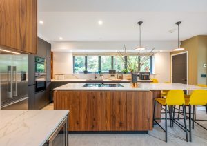 Walnut and matte black modern kitchen with island and yellow stools