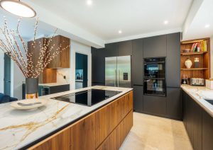 Walnut and matte black modern kitchen with island and hob and yellow stools